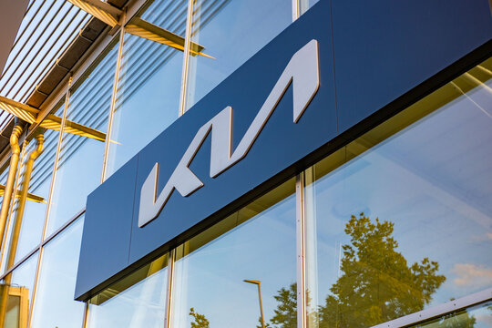 Kia dealership exterior corporate logos modern glass facade, European automotive retail center reflecting sky, mobility business car sales, global manufacturer, Recognizable branding F&uuml;ssen, Germany
