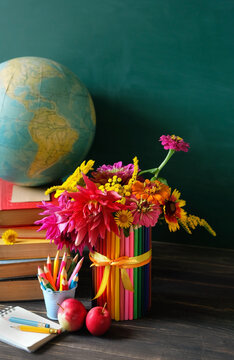 Education, back to school, beginning of the school year, Teacher's day, Knowledge Day, 1 September concept. learning books, globe, school stationery, apples, flowers on table against chalkboard