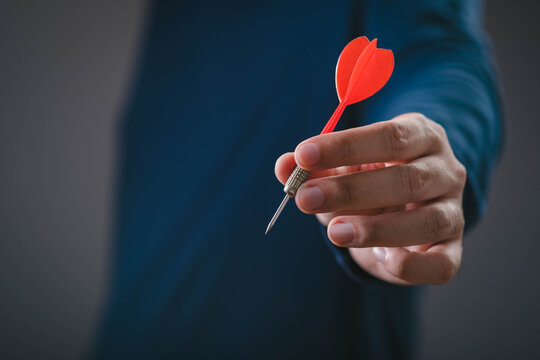 Business professional holding a red dart, illustrating goal setting, target achievement, business strategy, success planning, precision, focus, leadership, performance improvement and strategic growth