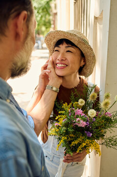 Romantic Moment Between Asian Woman And Partner With Wildflower Bouquet On A Summer Street