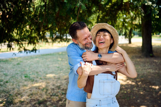 Happy Mixed Couple Embracing in Park &mdash; Asian Woman and Man Laughing Together Outdoors