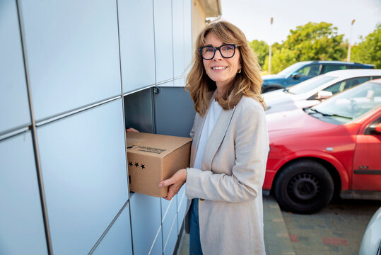 Woman picking up a parcel from an outdoor parcel locker