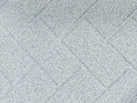a repeating geometric pattern of grey concrete stone pavement blocks in a diagonal grid layout, showing rich speckled natural texture and crisp geometric lines.