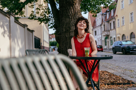 Stylish Mature Woman Enjoying Iced Matcha at Outdoor Cafe in European City