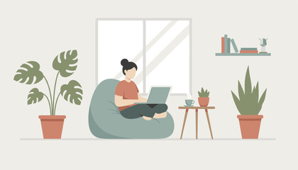 Fototapeta premium Young woman working on her laptop while sitting in a cozy bean bag chair at home surrounded by beautiful houseplants.