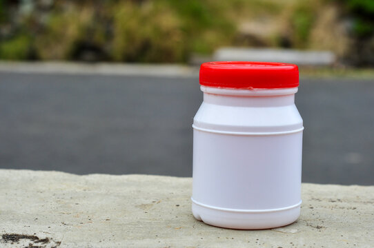 Blank White Plastic Bottle with Red Cap Outdoors