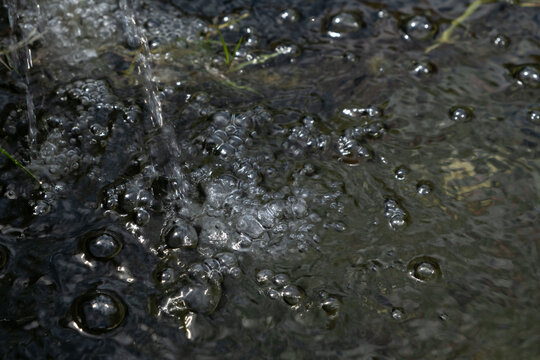 Close-up of Water Splashing with Air Bubbles and Foam on Dark Water Surface