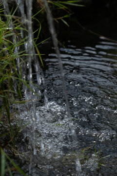 Small Waterfall Splashing Fresh Water into Pond with Air Bubbles