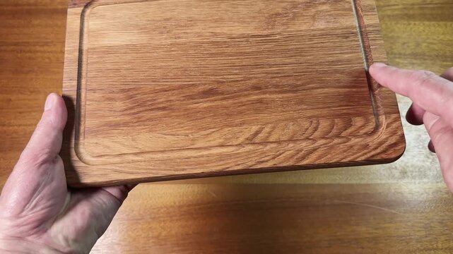 Oak cutting board with groove in hands above wooden table