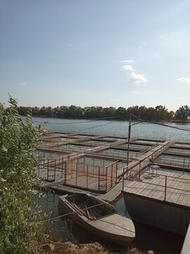 Fish farm cage culture on river for sturgeon and fish breeding with metal cages and wooden pontoon