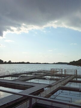 ​Fish farm cage culture on river for sturgeon and fish breeding with metal cages and wooden pontoon and sunset. 