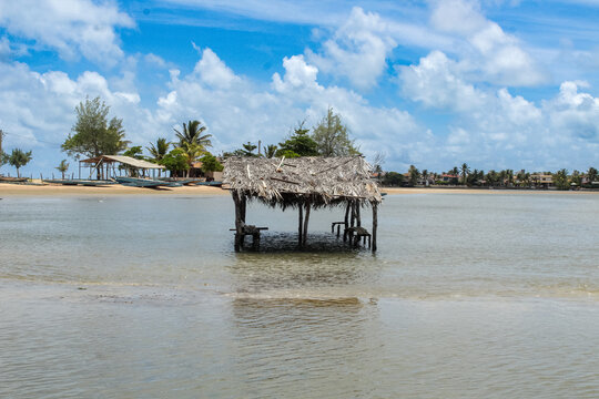 Rustic thatched wooden hut standing in shallow tropical water in Brazil