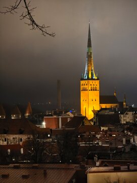 Night view of illuminated St. Olaf's Church spire and rooftops in Tallinn Old Town, Estonia.