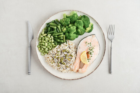 Balanced healthy meal with baked salmon with brown rice and vegetables