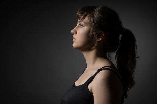 Portrait of a beautiful teenage girl posing in profile against a dark background