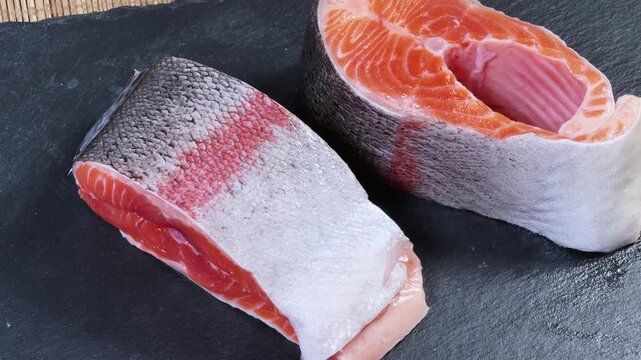 Pieces of raw rainbow trout on flat black slate plate
