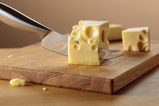 Cheese and knife on a wooden cutting board.