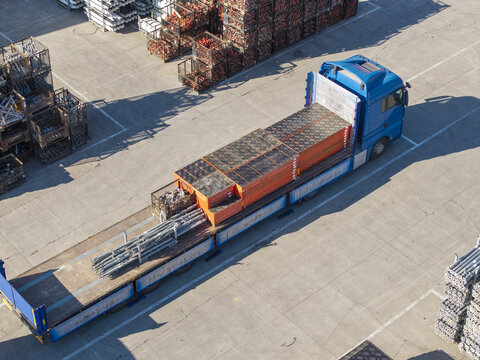 Jaworzno, Poland - 09 August 2026: Aerial view of PERI Polska facility with a blue truck loaded with construction formwork and scaffolding materials in an industrial yard.