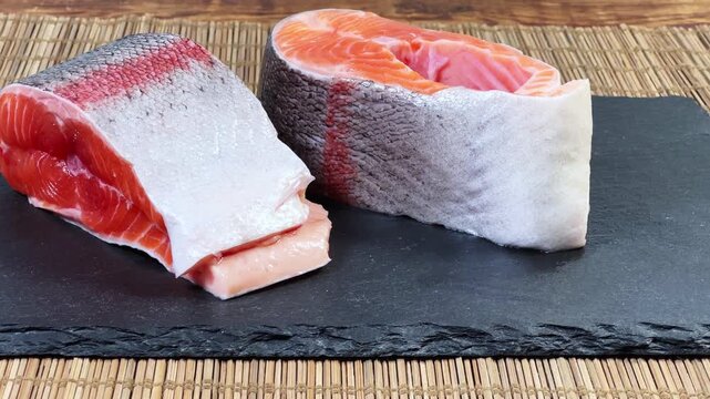Pieces of raw rainbow trout on flat black slate plate