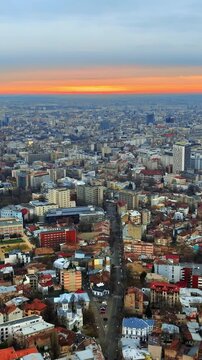 Bucharest skyline aerial drone view at sunset with city traffic and colorful orange horizon in Romania.