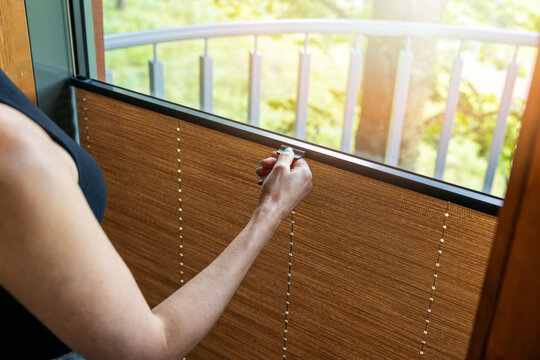 woman hand adjusting pleated window blinds to control daylight at home