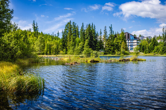A serene alpine lake New Strbske pleso of glacial origin in National Park High Tatra, Slovakia, reflects the clear blue sky and surrounding evergreen trees