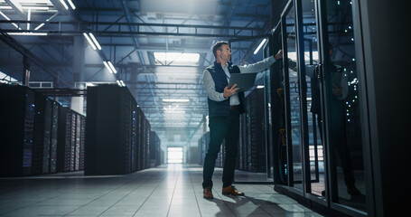 Obraz na płótnie Canvas Caucasian Male It Administrator Standing and Opening Glass Server Rack Cabinet Door While Holding Laptop Computer, Specialist Performing Equipment Audit and Firmware Upgrade in AI Data Center