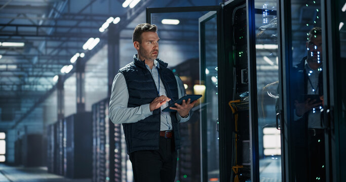 Portrait of Caucasian Male Data Center Technician Standing Beside Open Server Rack Cabinet Using Digital Tablet Computer for Equipment Inspection and Capacity Monitoring in AI Cloud Computing Facility