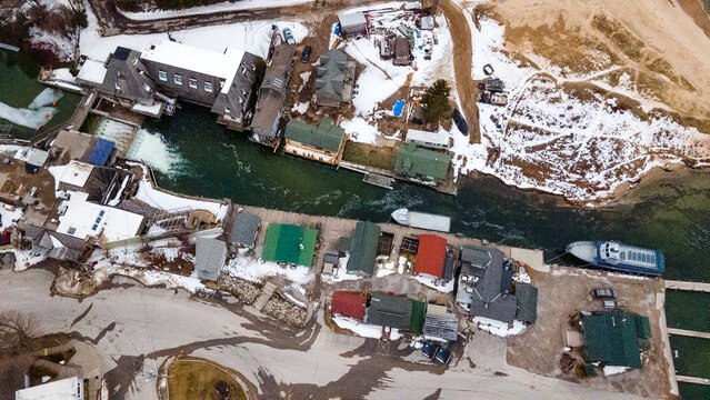 Leland, Michigan, United States - 03 March 2021: Aerial view of Historic Fishtown with its iconic weathered shanties, fishing boats, and snow-covered docks along the river in winter.