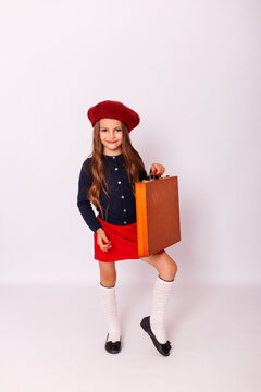 Full length portrait of cute little girl in red beret holding wooden suitcase