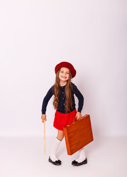 Full length portrait of cute little girl in red beret holding wooden suitcase