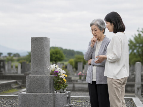 Elderly Mother and Adult Daughter Discussing a Family Grave in Cemetery
