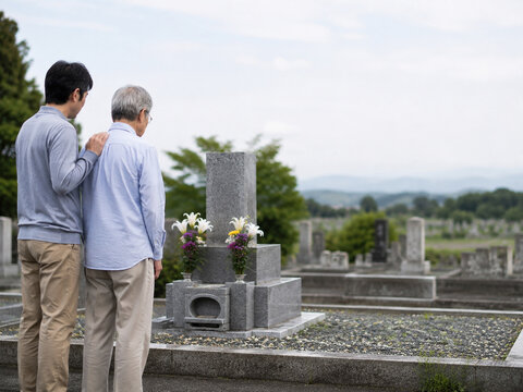 Adult Son Supporting Elderly Father During Family Grave Visit