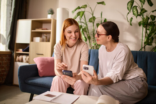 Mature mother and adult daughter discussing mobile transaction. Concept of shared responsibility for senior finances and family banking support.