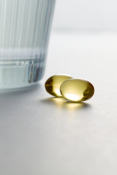 Two Omega 3 Fish Oil Capsules with a Glass of Water
