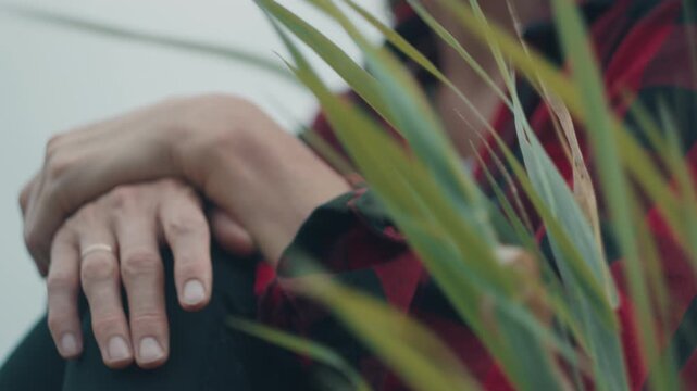Close-up of green riverside grass in sharp focus with a woman in a red plaid shirt blurred in the background