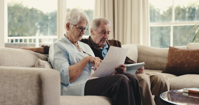 Tablet, document and old couple stress with discussion for bills mistake, error and confused in home. Married, senior people and paperwork on couch with tech, utility expense and doubt for liability.