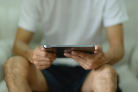 Close-up of a person using a tablet device while sitting casually indoors
