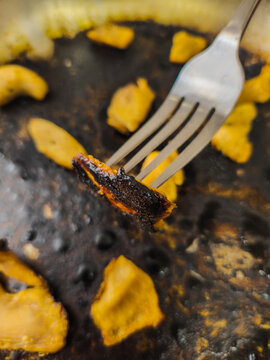 Close-up of Burnt Food on Fork from Greasy Cooking Surface
