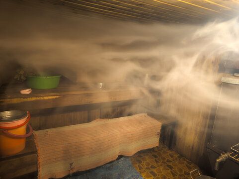 Interior of a Steamy Sauna with Wooden Benches and Accessories