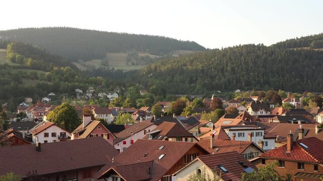 Time-lapse 4K montrant la tomb&eacute;e de la nuit sur les toits du village de Couvet, dans le Val-de-Travers en Suisse. La lumi&egrave;re du jour diminue progressivement tandis que les nuages se d&eacute;placent dans le 