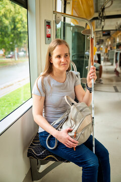 Blond haired blind woman with her white cane sitting on the tram