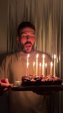 A young man with a beard, who looks like a Scandinavian, is blowing out the candles on a birthday cake. It s his birthday a day when it s traditional to make a wish, and there s a surprise
