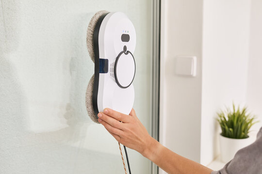 Hand activating an innovative automatic window cleaning robot, enhancing home hygiene and efficiency while effortlessly maintaining glass surfaces