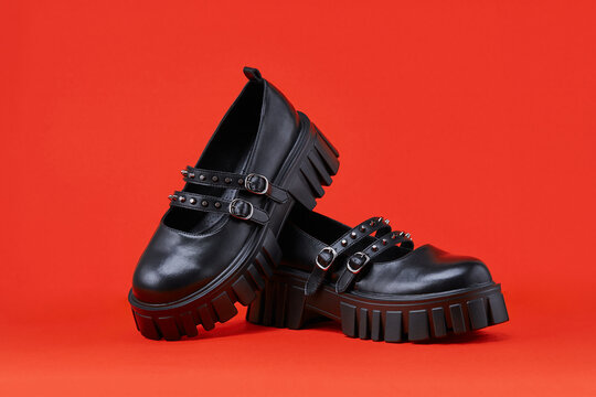 Black women's shoes on a red background. Teenage modern shoes made of genuine leather.