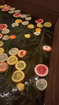 A close-up of a wooden tub filled with citrus fruits and fir branches, enjoying a moment of relaxation in the countryside. Outdoor bath, steam bath, and sauna
