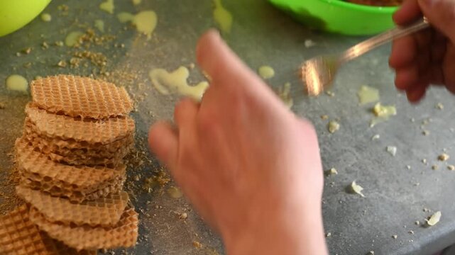 Cook puts raw minced meat on crispy waffle sheet with fork. Person prepares delicious waffle meat cutlets inside kitchen room. Homemade cooking process includes fresh ingredients.