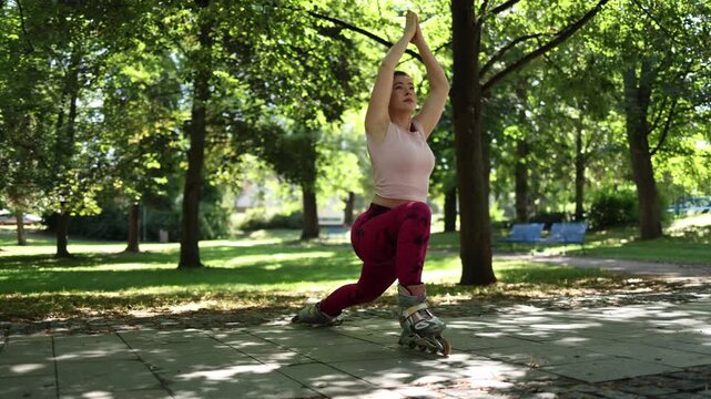 Athletic woman performs a deep lunge stretch on inline skates in a green park combining flexibility balance and mobility training during an active outdoor workout session