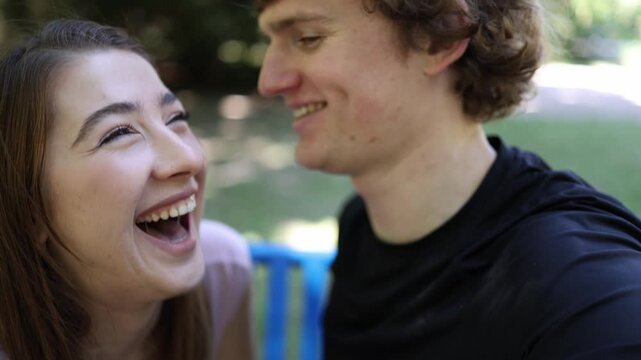 Young woman gives a playful flirty smile while sitting close to a man outdoors showing romantic attraction chemistry affection and excitement during a new relationship as