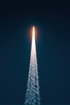 ww3 missile launch, slender rocket rising vertically into dark blue sky with white plume, photorealistic